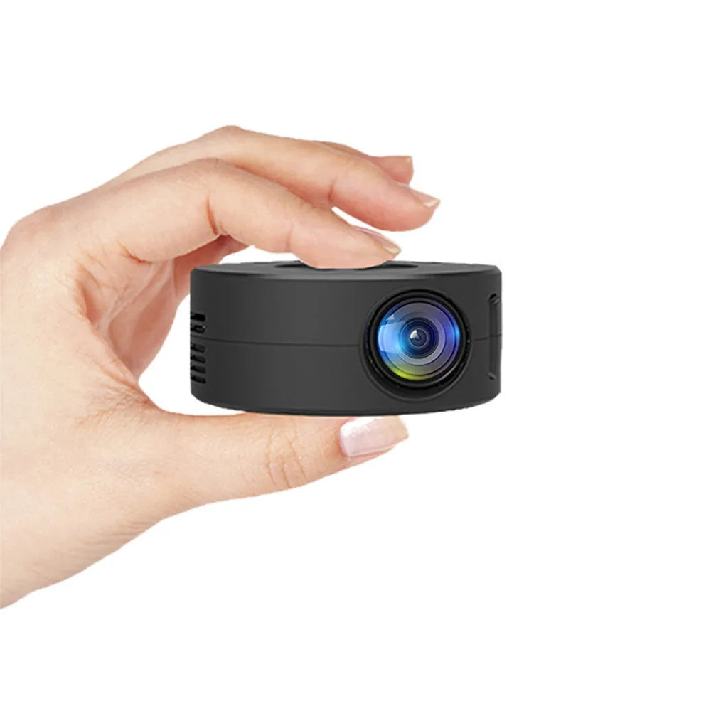 Black portable mini projector for children next to a smartphone for scale