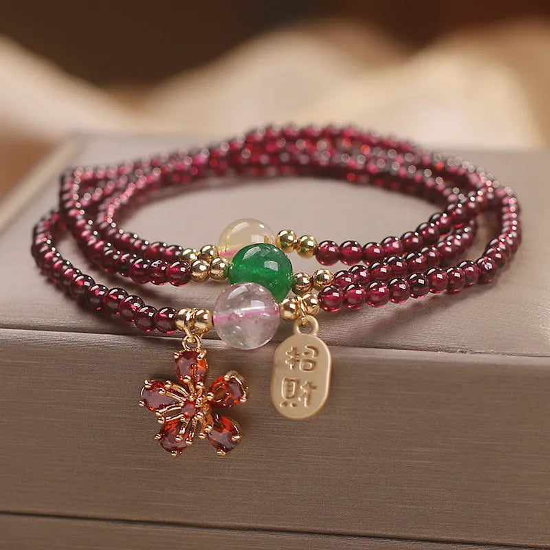 Women's crystal bracelet with pomegranate red cherry blossom beads and sequin details on a simple band.