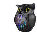 Black plastic owl-shaped portable Bluetooth speaker on a table.