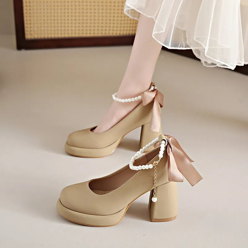 Beige women's Mary Jane shoes with a chunky heel, round toe, and pearl-decorated ankle strap buckle on a white background.