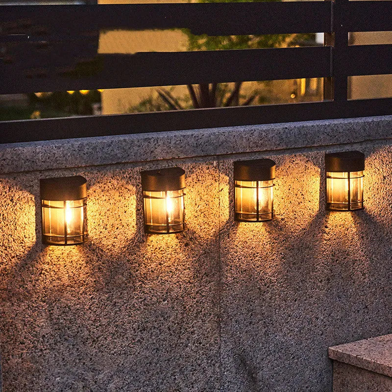 Tungsten-style solar-powered outdoor wall light with automatic light sensor mounted on a garden wall.