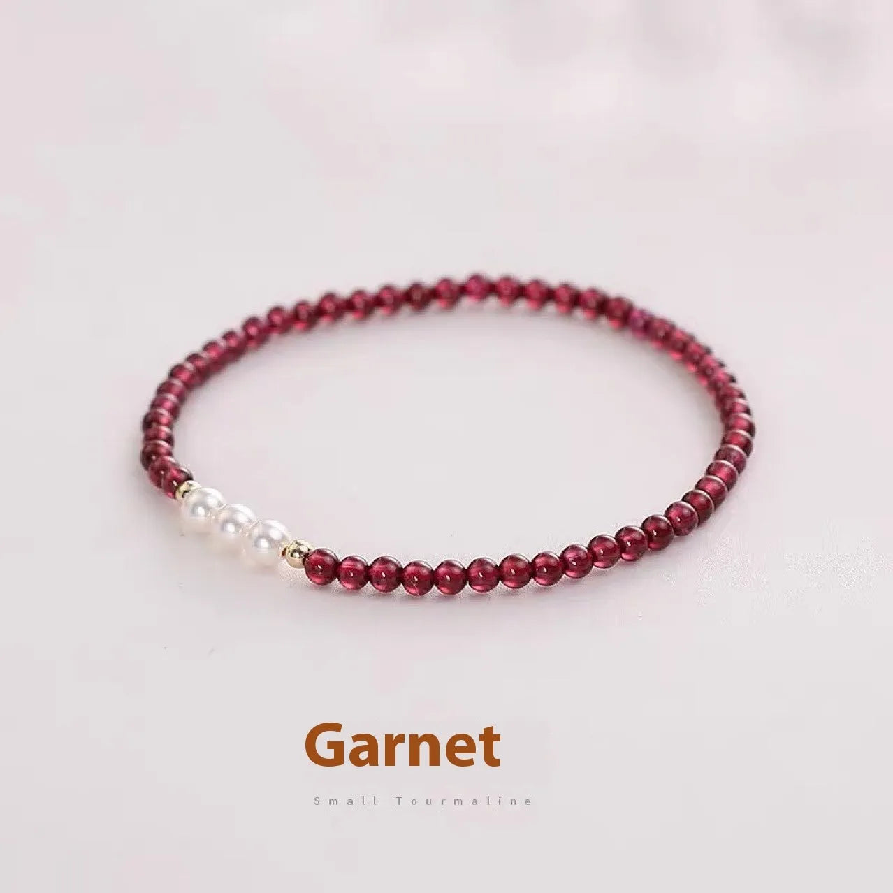 Close-up of a women's adjustable crystal bracelet with red garnet and white artificial pearl beads.