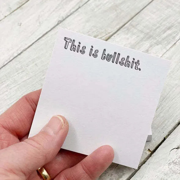 Square 7.5cm sticky note pad with adhesive strip and printed English text on cover.