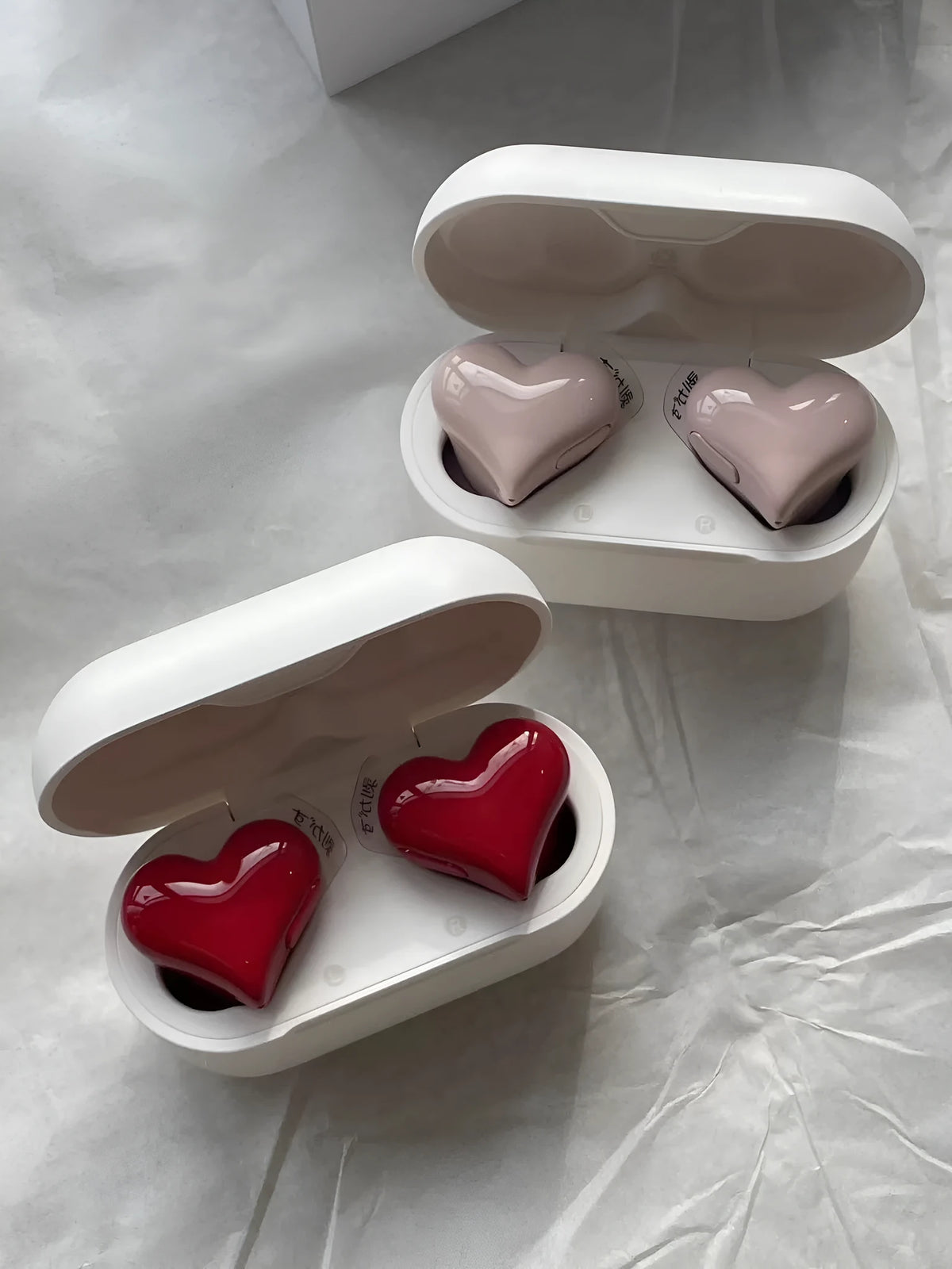 Heart-shaped wireless Bluetooth headphones in red or pink colour with charging cable