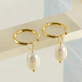 Gold geometric earrings with freshwater pearl accent on stainless steel background