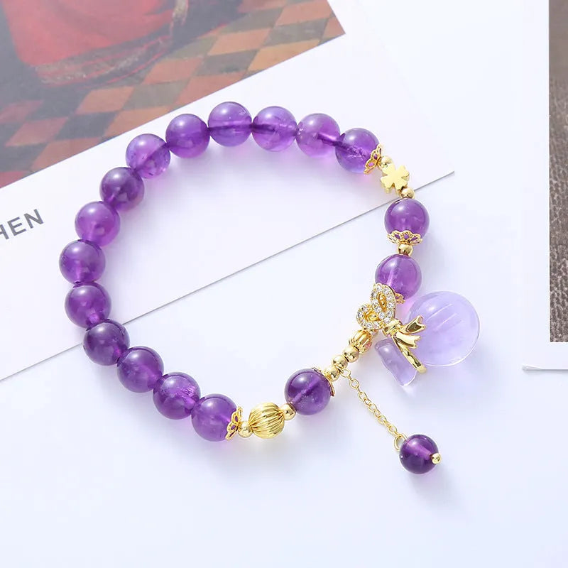 Purple amethyst bracelet with detailed money bag charm and peace buckle pendant on wrist