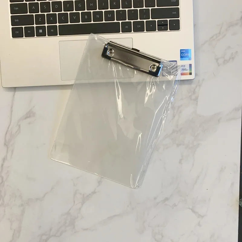 Clear A4 plate holder with metal clip and transparent writing pad in blue colour on a desk.