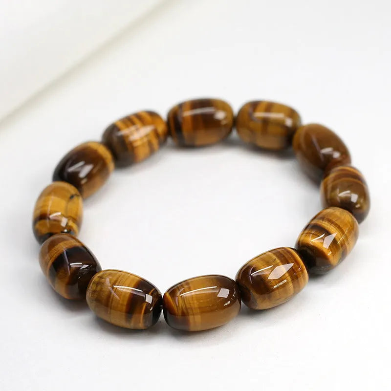 Close-up of a natural yellow Tiger Eye gemstone beaded bracelet with cat's eye effect on a wrist.