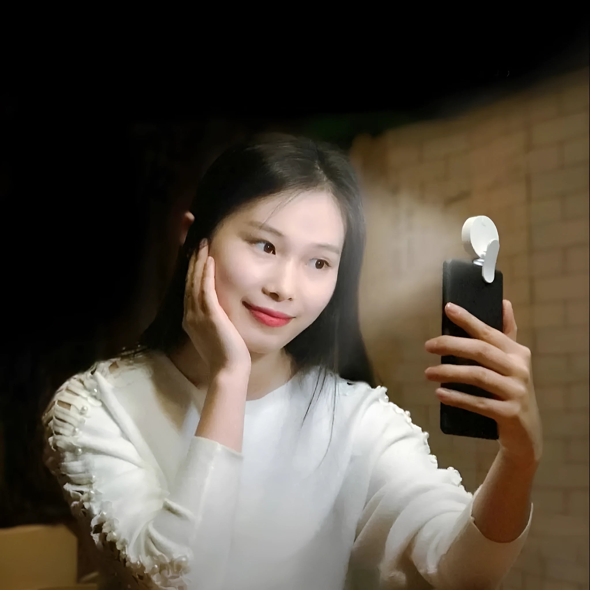 White clip-on LED selfie light for mobile phones showing three-level dimming buttons and USB port.