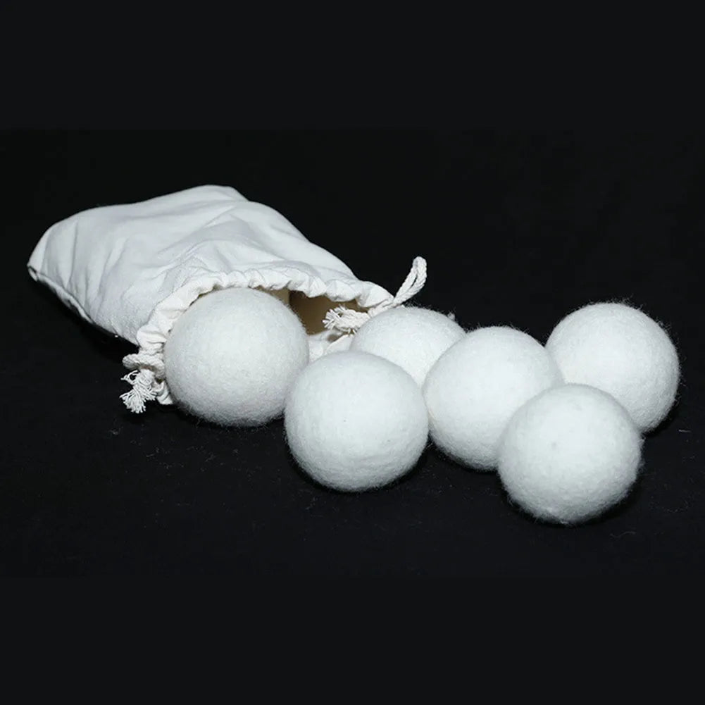 Set of 100% wool anti-static drying balls next to a plain cotton storage bag on a laundry background.