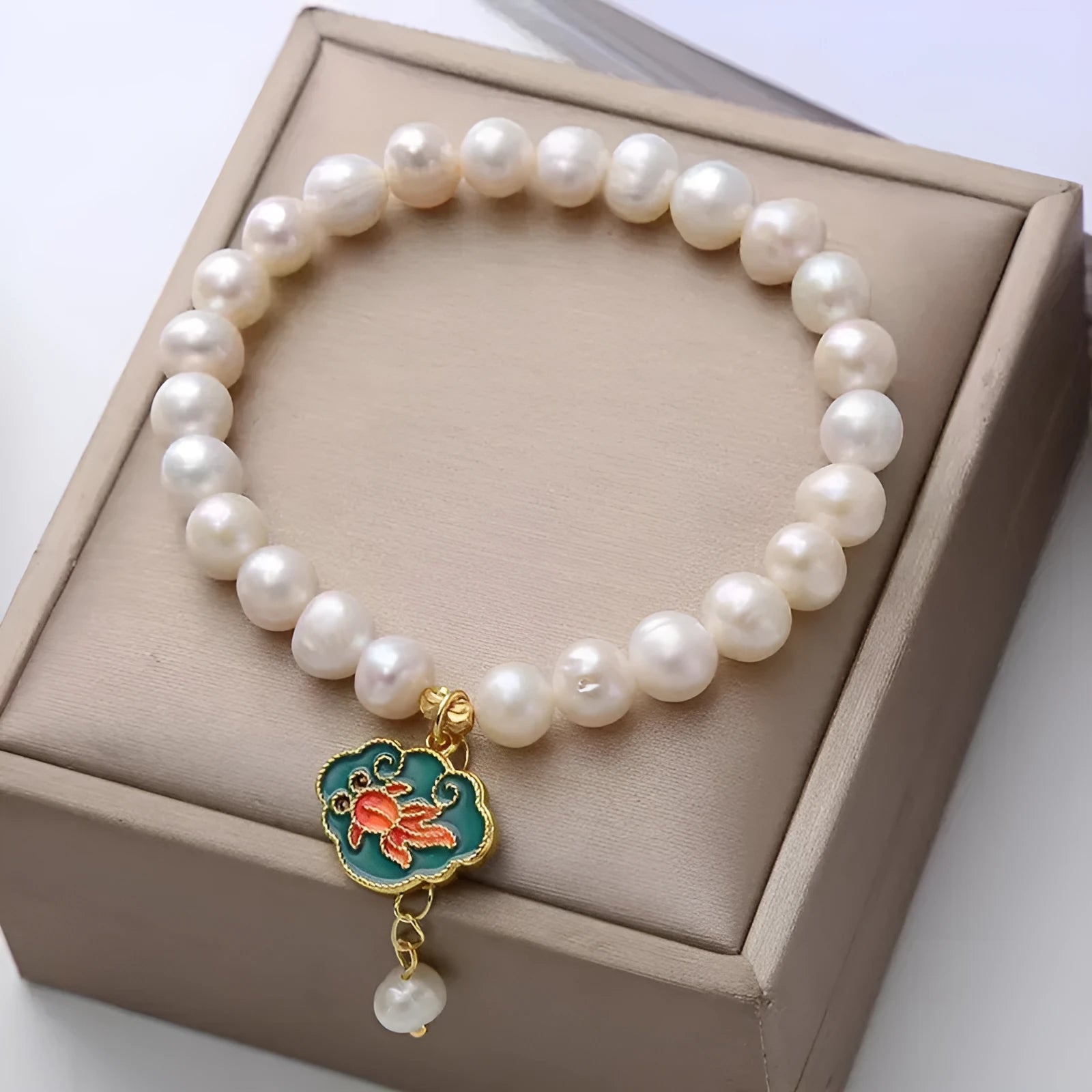 White freshwater pearl and gold electroplated lotus goldfish pendant on an antique style women's bracelet.