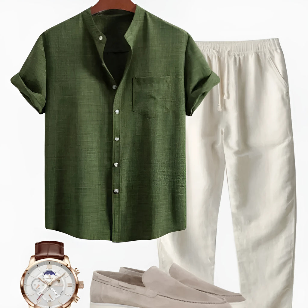 Man wearing a blue slim-fit stand collar short-sleeved shirt and trousers from a coordinated set with shoes and watch.