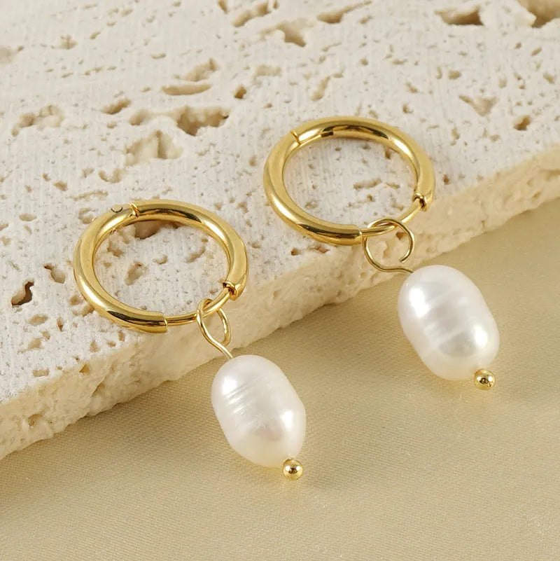 Gold geometric earrings with freshwater pearl accent on stainless steel background