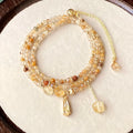 Gold three-circle layered bracelet with caramel citrine stones and a Saturn charm.