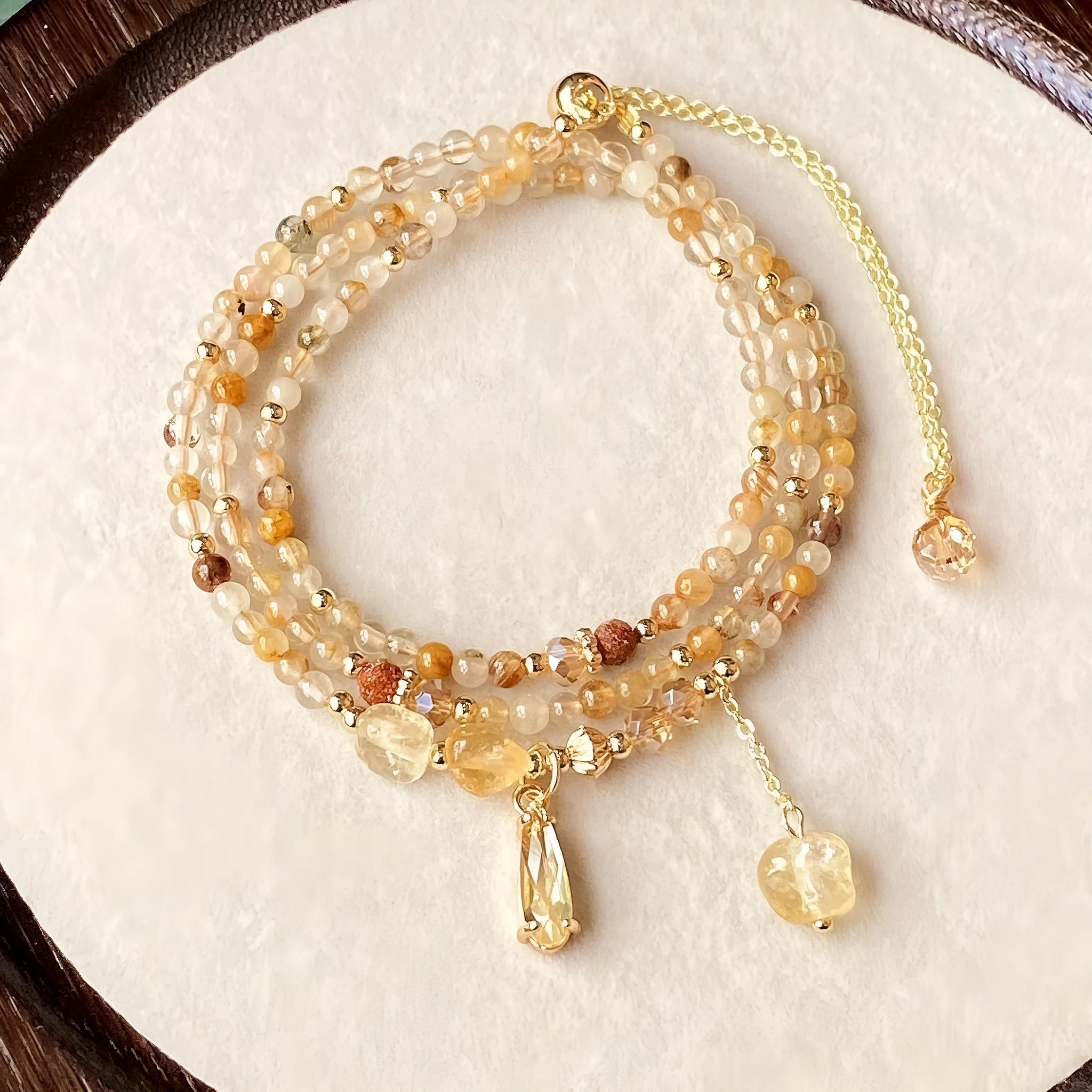 Gold three-circle layered bracelet with caramel citrine stones and a Saturn charm.