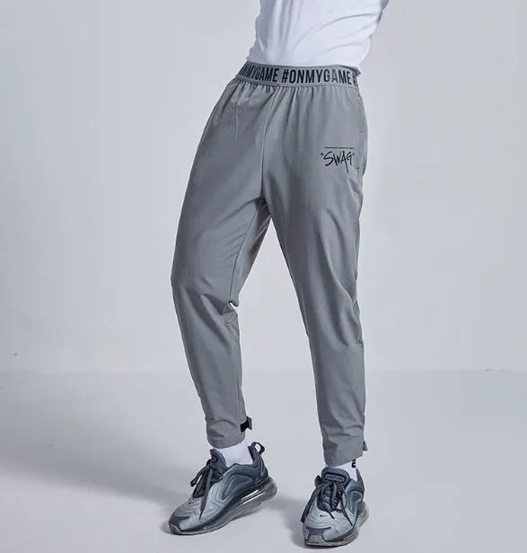 Loose fit grey sports cropped pants with a printed elastic waistband, shown on a model.