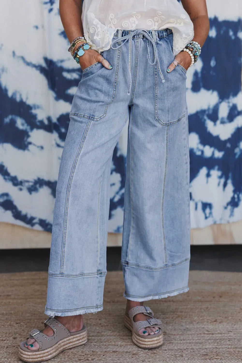 Beau blue wide leg denim pants with drawstring waist and raw hem detail laid flat