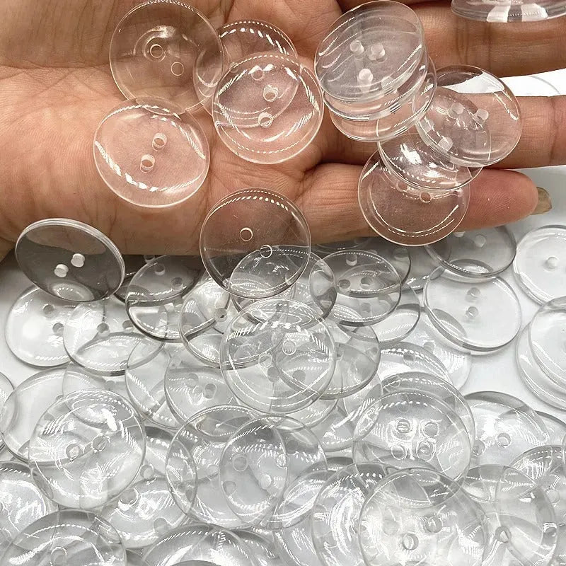 Close-up of a transparent, two-hole resin sewing button measuring 10mm in diameter.