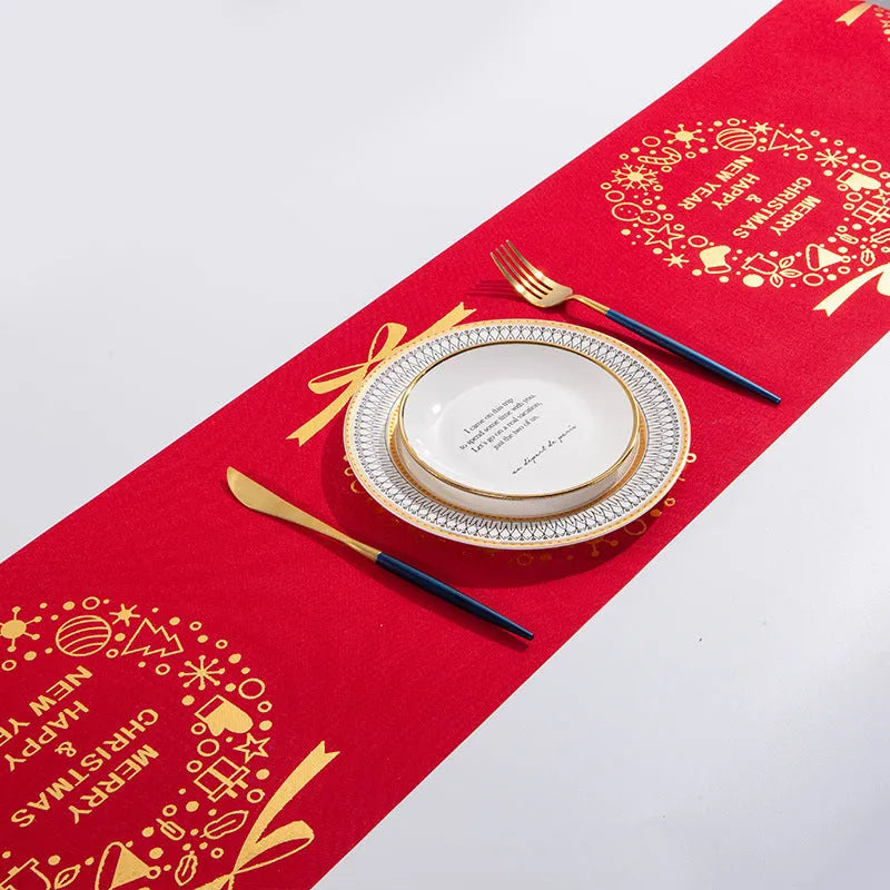 Red, white, and green Christmas table runner with elk and snowman print on a wooden dining table.