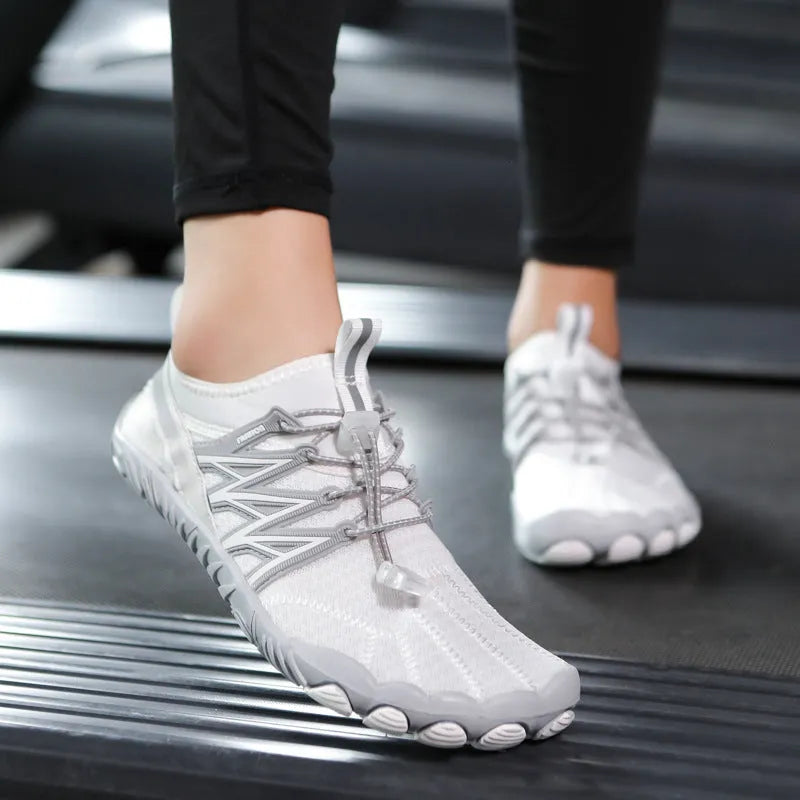 Low-top black and grey indoor training sneakers with mesh upper and rubber sole on a gym floor.