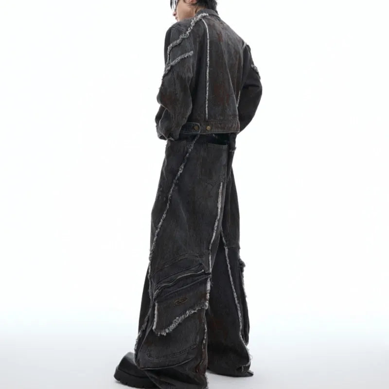 Black gradient denim coat with distressed raw edges and padded shoulders, worn with matching black denim trousers.