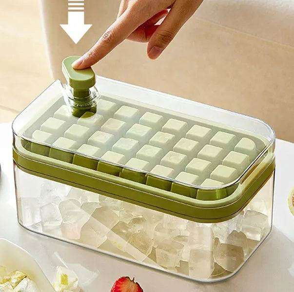 Green one-button press ice cube mould with transparent lid and ice shovel on a kitchen counter