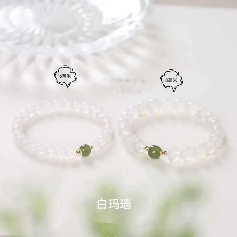 Handmade natural white agate and Hetian jade crystal bracelet with cinnabar inlay on a wrist.