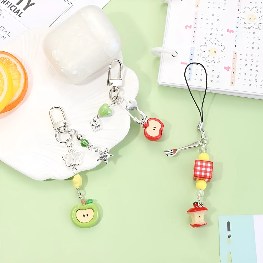 Red and green fruit-themed plastic mobile phone charm and keychain on a white background.