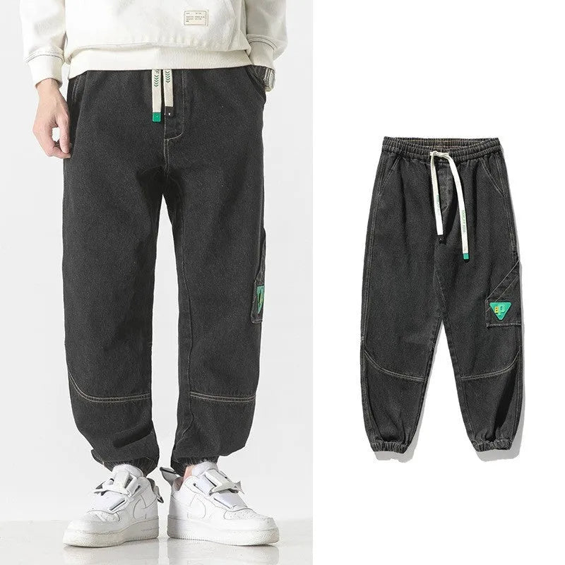Men's loose-fit tapered trousers in 100% cotton, available in black, blue, and grey colours, showing tapered leg design.