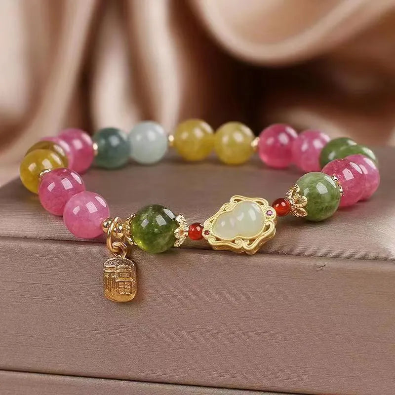 Close-up of a women's bracelet with a colourful tourmaline gourd charm and electroplated floral links.