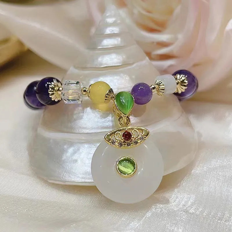 Purple amethyst bracelet with detailed money bag charm and peace buckle pendant on wrist
