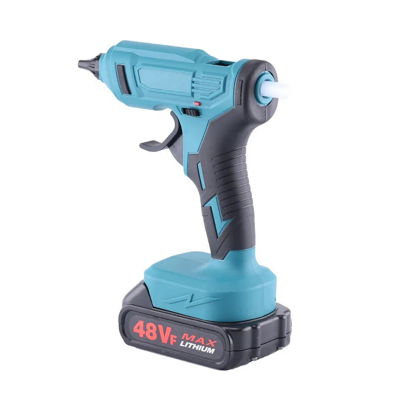 Cordless hot glue gun with two batteries, a charger, and a pack of glue sticks on a workbench.