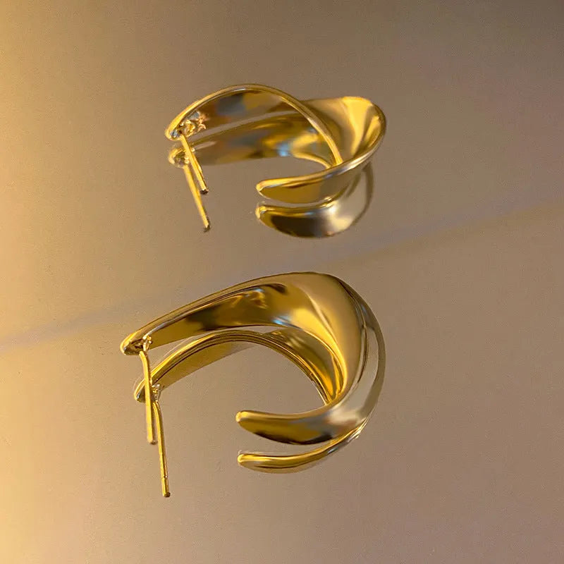 A pair of twisted geometric design metal earrings in gold or silver electroplated finish.