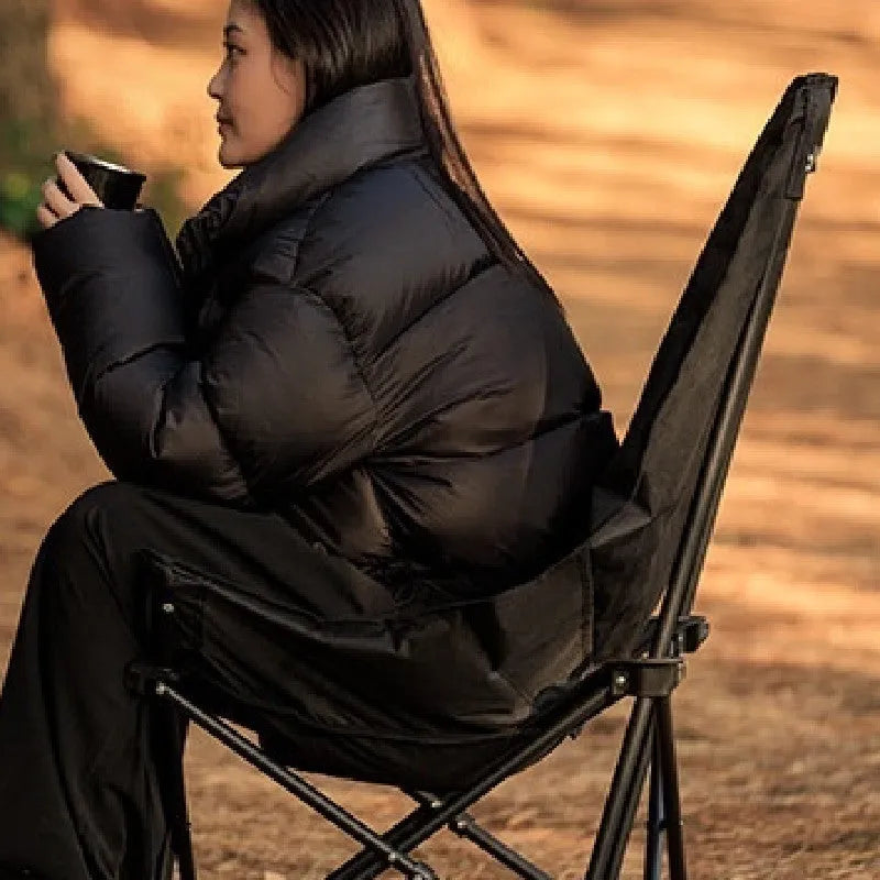 Black folding camping recliner with Oxford cloth seat, shown in outdoor setting
