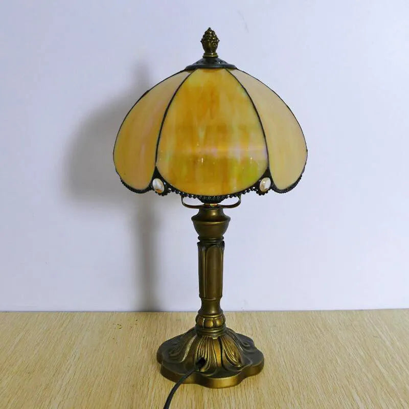 Beige fabric bedside lamp with 20cm wide shade on a table.