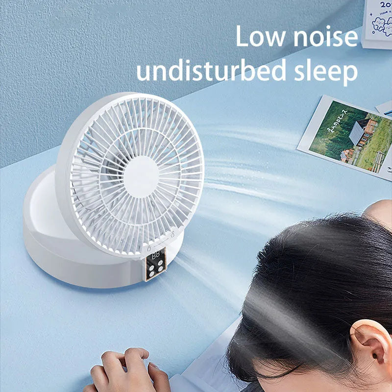 White portable USB rechargeable fan with remote control on a desk, showing its folding head and night light.