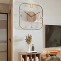Modern square wooden wall clock with transparent frame on a wall.