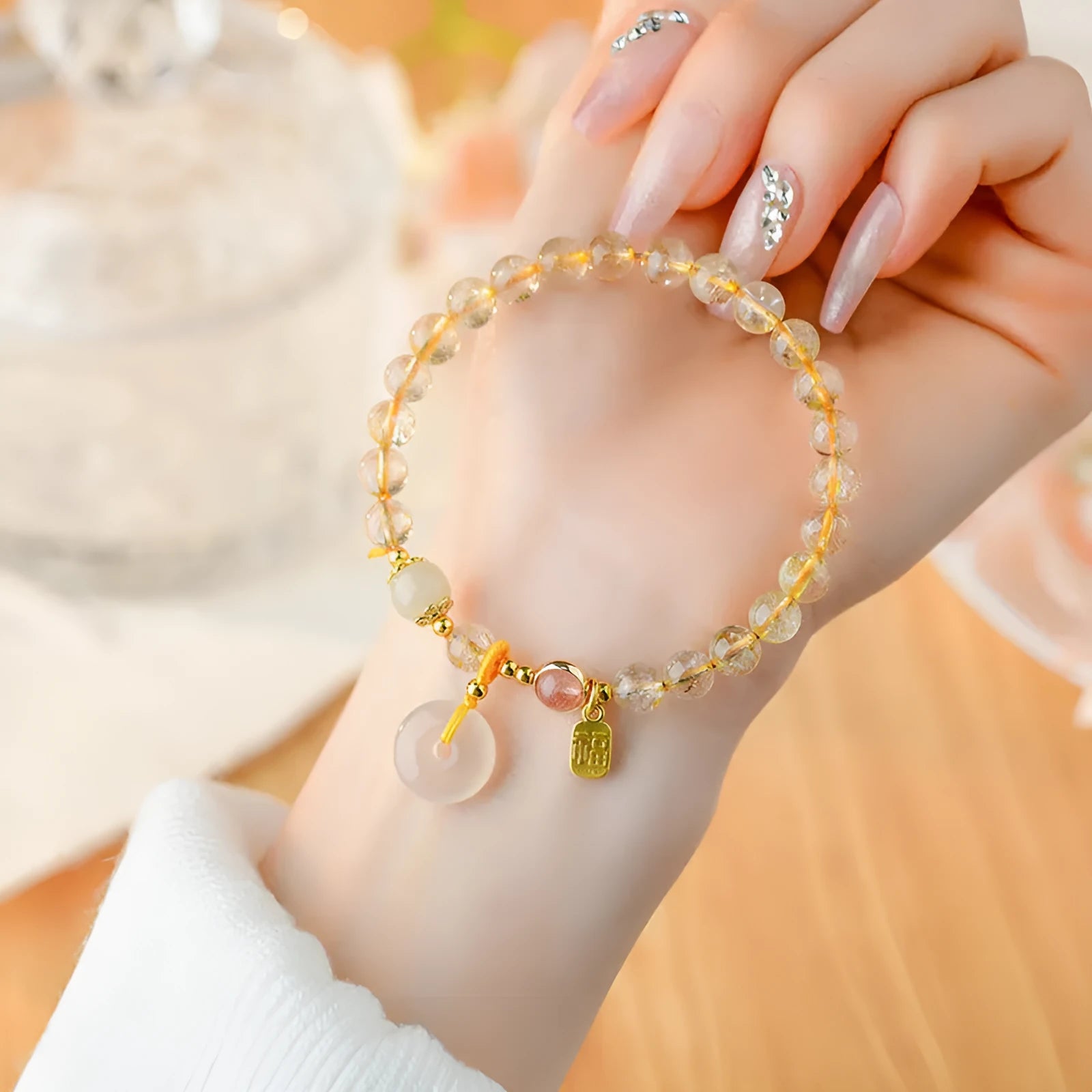 Gold rutilated quartz crystal bracelet with a safety buckle and a small rectangular blessing card pendant.