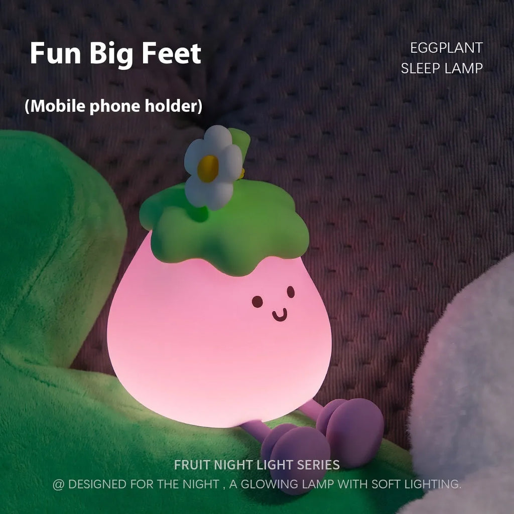 Cartoon-shaped eggplant night lamp glowing with soft yellow light on a table.