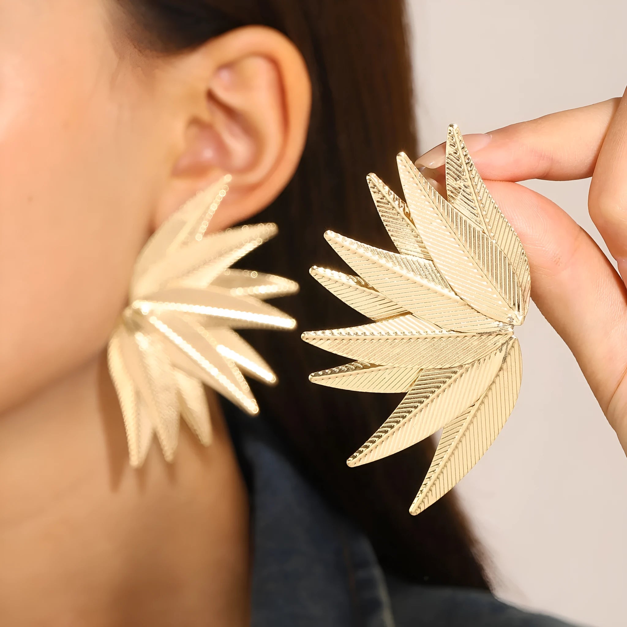 Gold and white alloy leaf-shaped stud earrings with botanical design