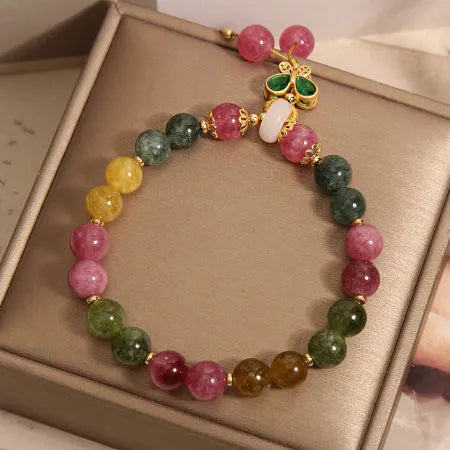 Colourful tourmaline butterfly pendant bracelet with rhinestone details on a woman's wrist.