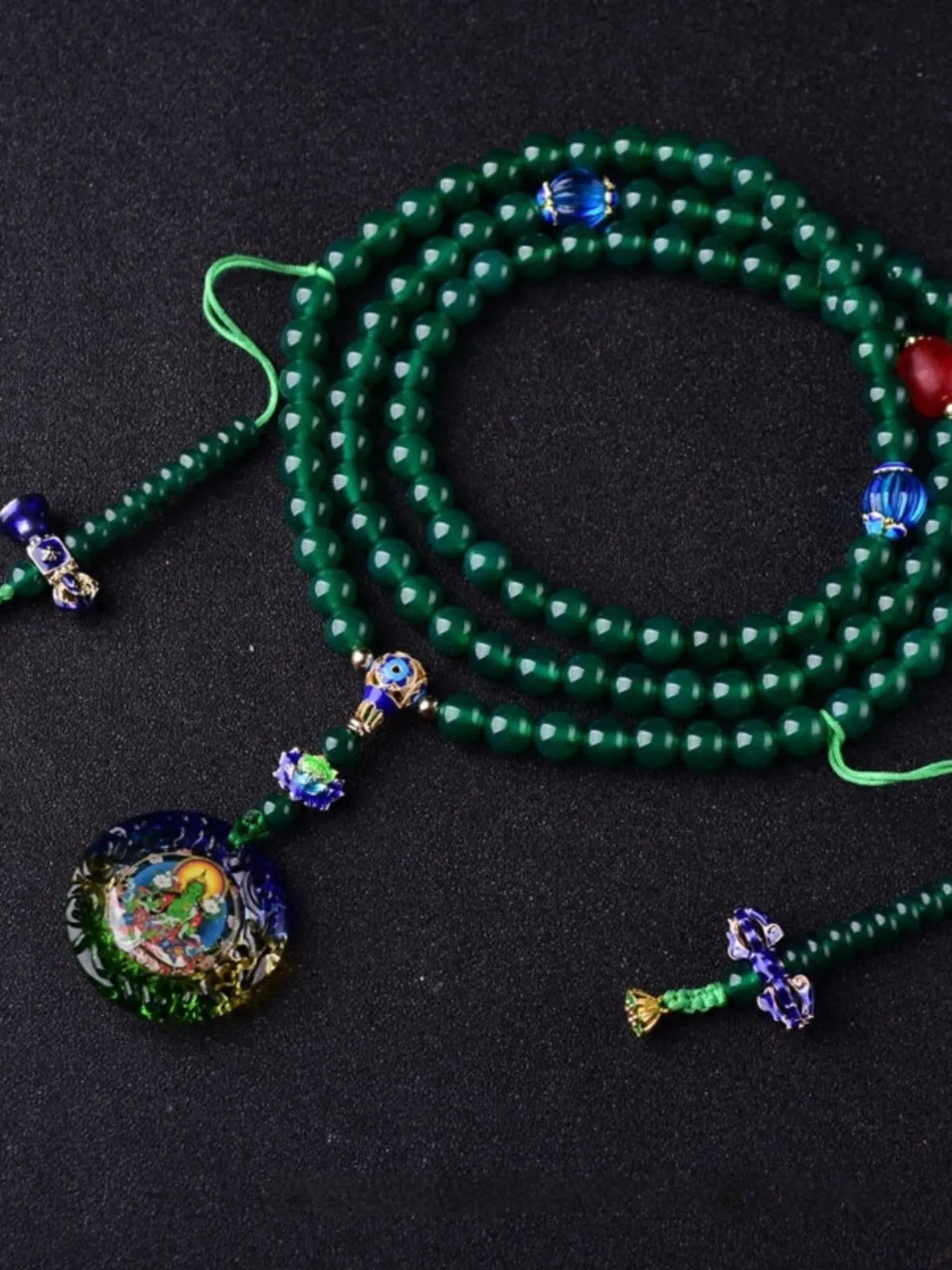 Green agate beaded bracelet with a multi-circle 108-bead thangka pendant on a wrist.