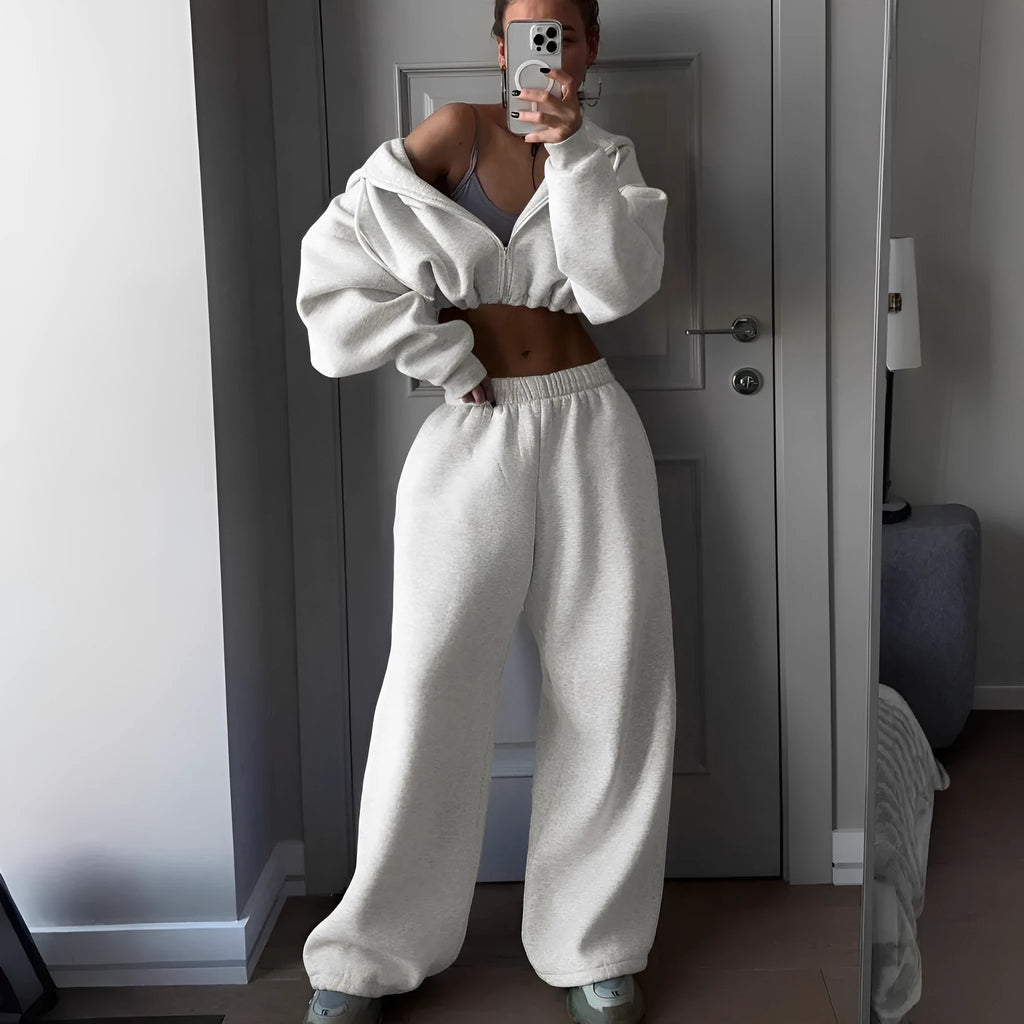 Man wearing a long sleeve sweater and matching trousers from a grey two-piece sports leisure suit set.
