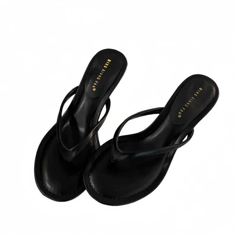 Women's black rubber stiletto flip-flops with round toe and flat head cap on a plain background.