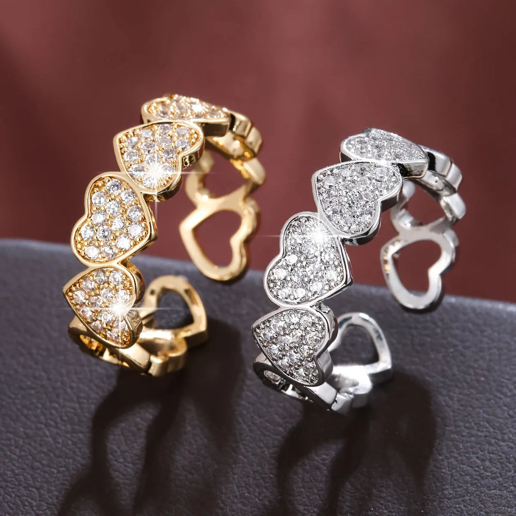 Adjustable geometric couples ring with love heart elements in gold or silver colour, showing opening mechanism