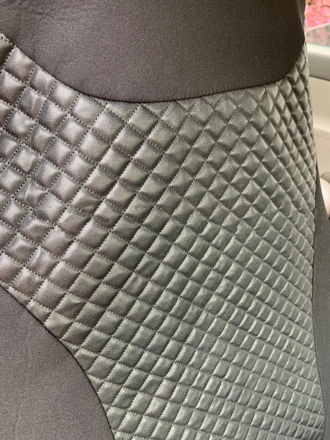 Black quilted automotive seat cover with PU and polyester fabric, showing sponge layer and plastic hooks