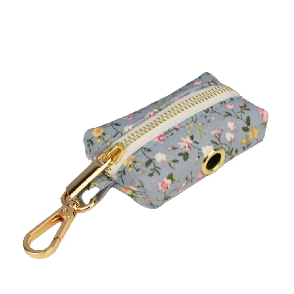 Blue floral pattern dog collar set with matching leash, vest, bow, and poop bag holder on wooden background