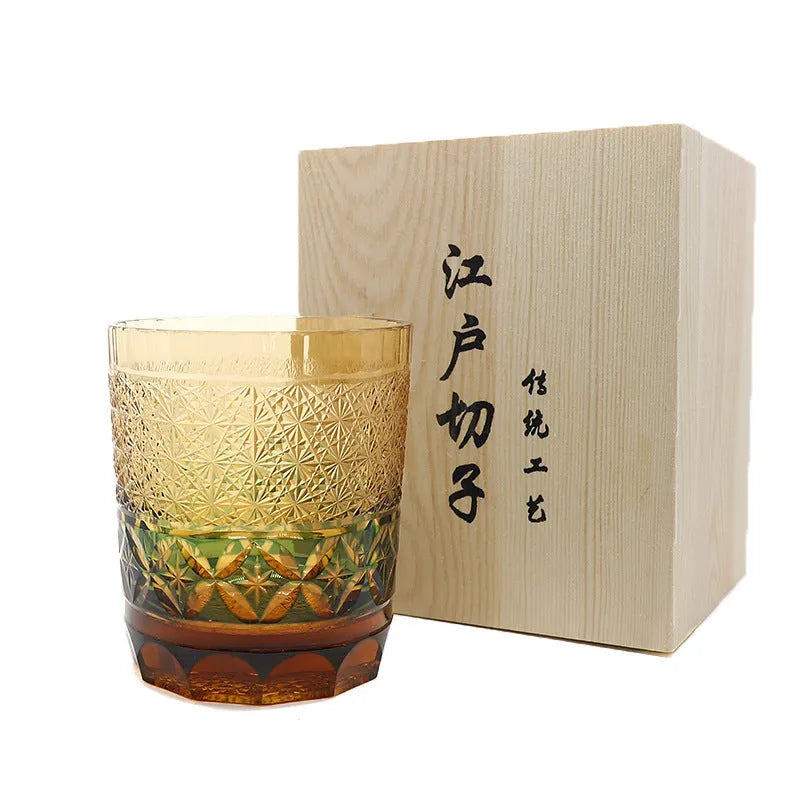 Hand carved Japanese style crystal whiskey glass in amber colour on a dark surface