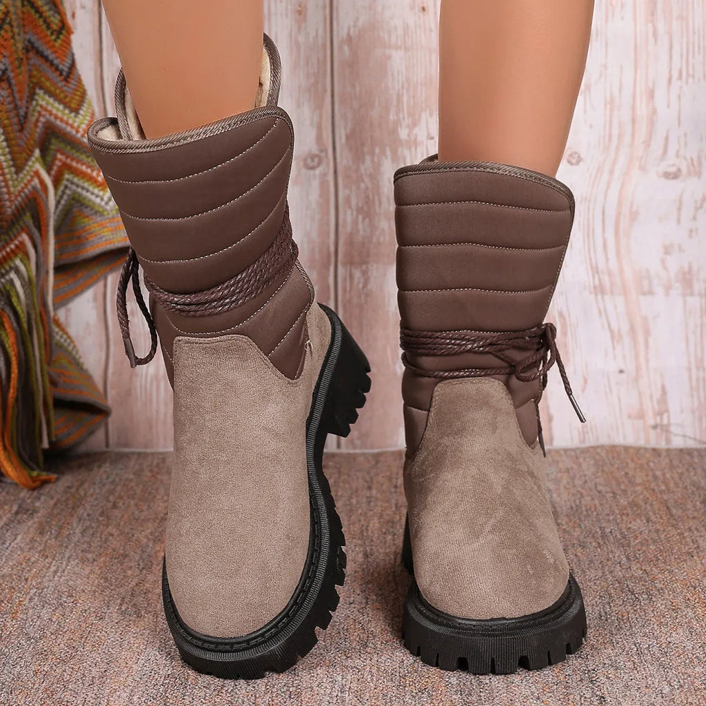 Women's black chunky heel snow boots with suede upper, rubber sole, and lace-up design on wooden floor