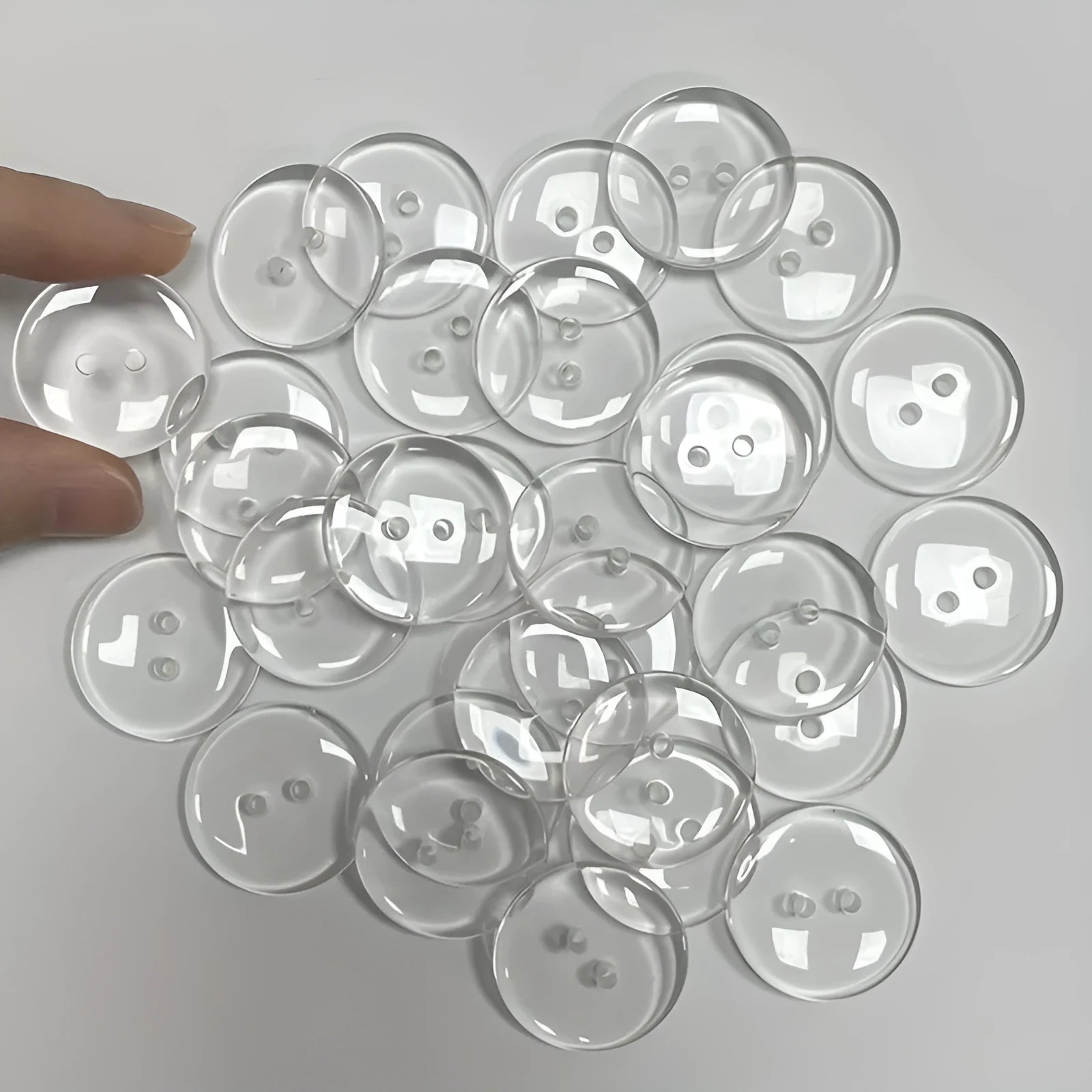 Close-up of a transparent, two-hole resin sewing button measuring 10mm in diameter.